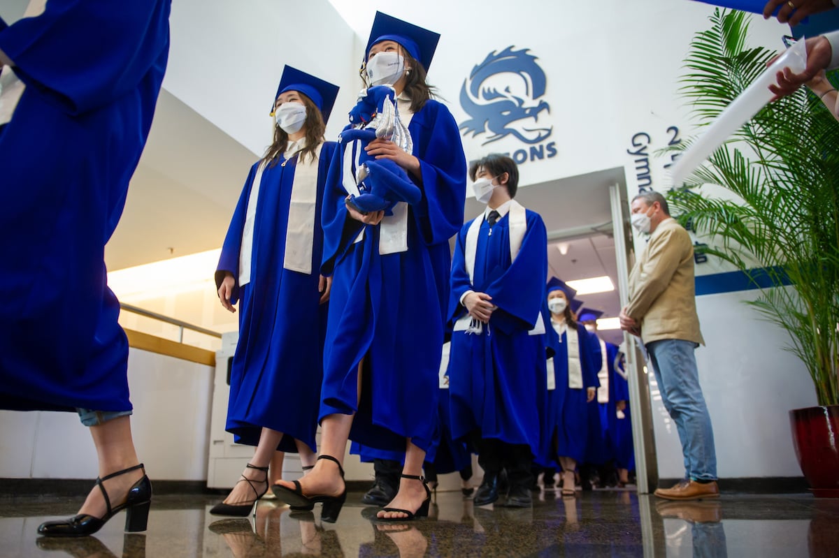 Students with graduation gowns walk in the in the 2022 Seniors Parade